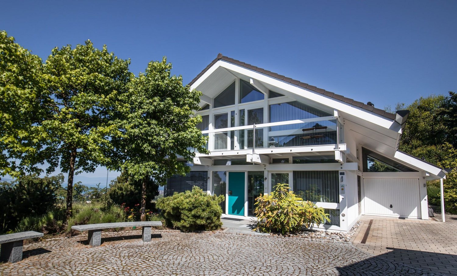 Stilvolles Haus mit großen Fenstern und grünem Umfeld