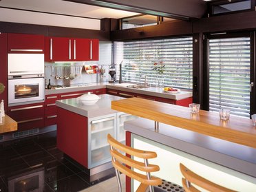 Moderne rote Küche mit offenen Fenstern und Barbereich Stylische Küche mit roten Schränken und Holzbar in modernem Design