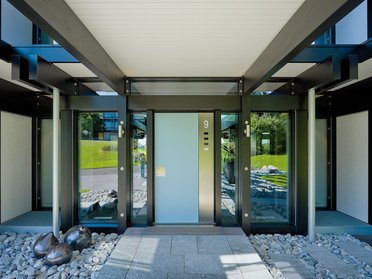 Eingangsbereich mit Glas- und Metallkonstruktion und Steinen
