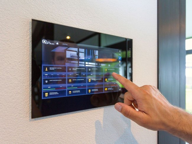 Hand bedient einem digitalen Steuerungspanel in einem stilvollen Architektenhaus