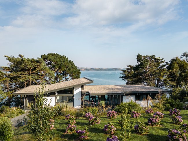 Spektakuläres Fachwerkhaus mit Meerblick Fachwerkhaus umgeben von Blumen und Bäumen mit Blick auf das Wasser
