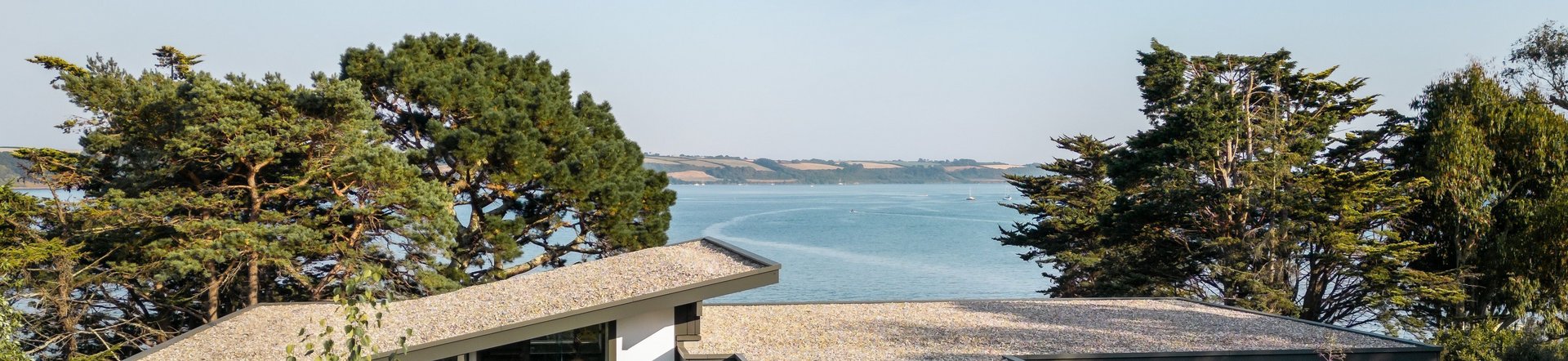 Fachwerkhaus umgeben von Blumen und Bäumen mit Blick auf das Wasser
