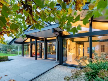 Bungalow mit organischen Formen und Glasflächen Moderner Bungalow in traumhafter Landschaft mit Bäumen und Wiesen