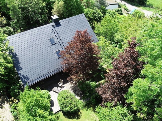 Luftaufnahme eines Hauses umgeben von Bäumen Haus mit modernem Dach, umgeben von üppigem Grün und Bäumen