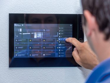 Benutzer steuert smarte Funktionen eines Familienhauses über ein Touchscreen-Panel