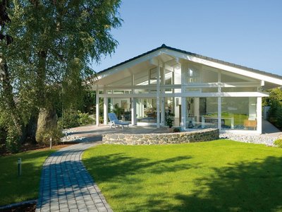 Moderne Architektur mit großzügigem Gartenbereich Helles Haus mit gläsernem Anbau und gepflegtem Rasen