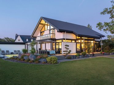 Moderne Architektur mit Gartenlandschaft bei Dämmerung Herausragendes modernes Wohnhaus mit Glasfront und stilvollem Garten