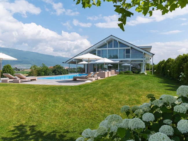Schickes Haus mit Pool, Sonnenschirmen und grüner Umgebung