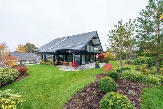 Zeitgenössisches Haus umgeben von grünem Garten und bunten Pflanzen