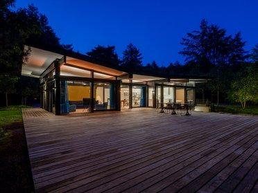 Modernes HUF Bungalow bei Nacht Stilvolles Traumhaus mit großer Terrasse und modernen Fenstern