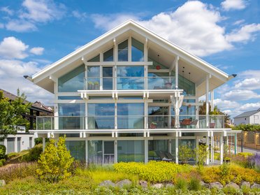Ein modernes Fachwerkhaus mit großen Fenstern und Gartenlandschaft