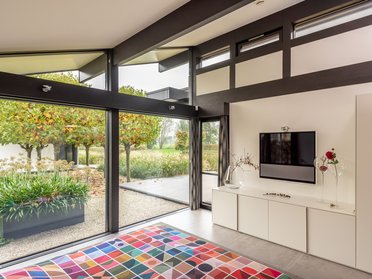 Ein Bungalow mit organischen Formen und Glasflächen in einer schönen Landschaft.