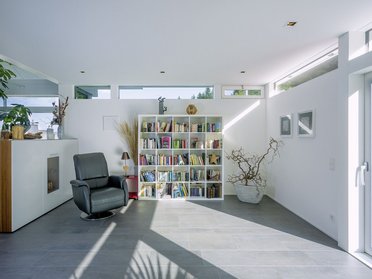 Heller Raum mit Bücherregal, bequemer Sessel und Pflanzen