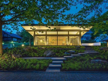 Moderne Villa bei Nacht mit Gartenbeleuchtung Stilvolle Architektur mit Glasfassade und umgebendem Grün