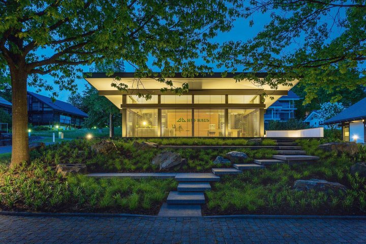 Moderne Villa bei Nacht mit Gartenbeleuchtung Stilvolle Architektur mit Glasfassade und umgebendem Grün