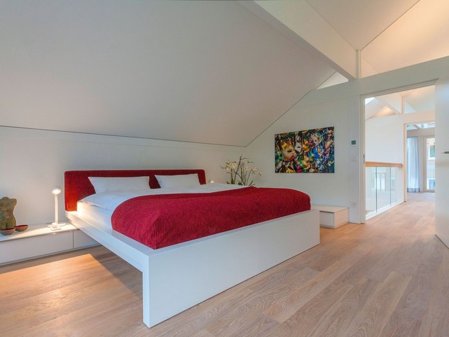 Helles Schlafzimmer mit rotem Bett und zeitgenössischer Kunst