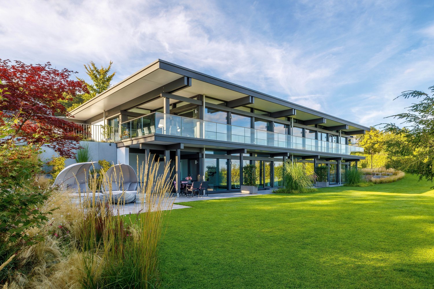 Modernes HUF HAUS mit großflächigen Fenstern und Flachdach.