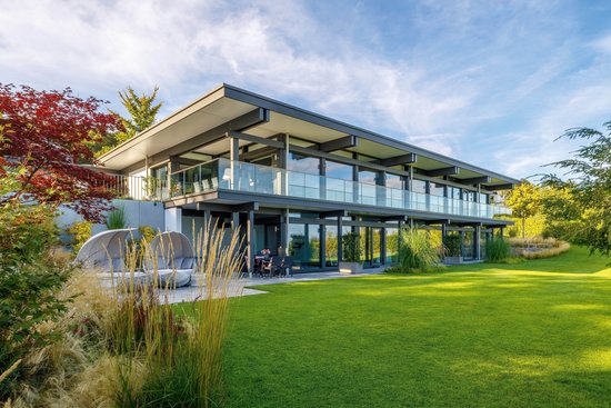Modernes HUF HAUS mit großflächigen Fenstern und Flachdach.