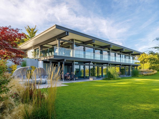 Modernes HUF HAUS mit großflächigen Fenstern und Flachdach.