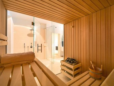 Gemütliche Sauna mit Holzbänken und Glasdusche in modernem Design