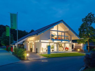 Beleuchtetes modernes Haus in ruhiger Umgebung bei Dämmerung