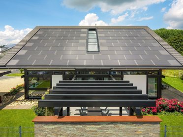 Konstruktionsansicht eines Hauses mit Solarpanelen und gepflegtem Garten