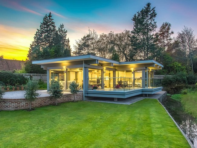 Stilvoller HUF Anbau erweitert Wohnraum Moderne Glasstruktur fügt sich harmonisch in die Landschaft ein.