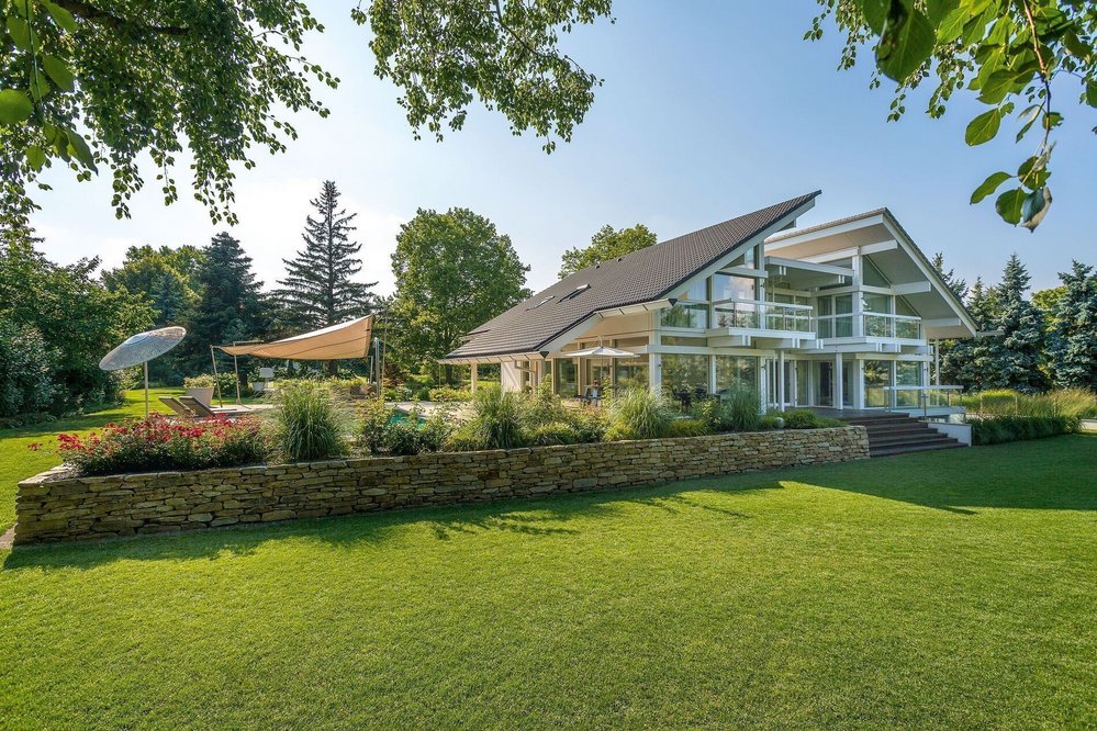 Weißes Fachwerkhaus im Grünen mit Doppelpultdach Moderner Garten mit großzügigem Fachwerkhaus und Terrassenflächen