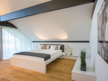 Helles Schlafzimmer mit Doppelbett, elegante Beleuchtung und Fenster