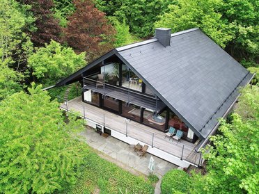 Moderne Architektur umgeben von Natur Ein modernes Holzhaus mit großem Balkon inmitten grüner Bäume