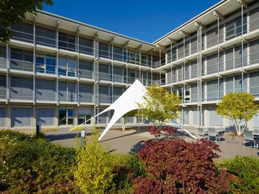 Ansicht des Bürogebäudes HUF mit Sonnensegel und Grünflächen