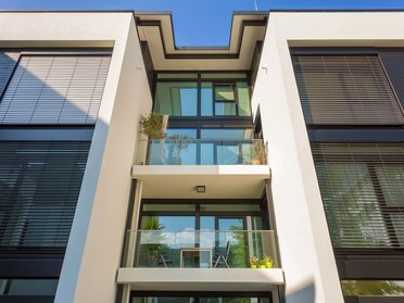 Fassade des Architektenhauses mit Glasbalkon und Jalousien