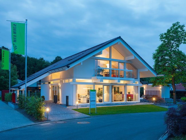 Futuristisches Haus mit großer Glasfront und beleuchtetem Garten