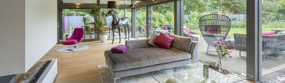 Modernes Wohnzimmer mit Gartenblick und stilvoller Einrichtung Helles Wohnzimmer mit Glasfront, bequemer Couch und designer Möbeln