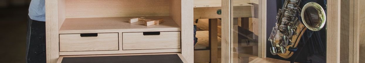 Handcrafted furniture display with saxophone Woodworkers beside a display case showcasing a saxophone