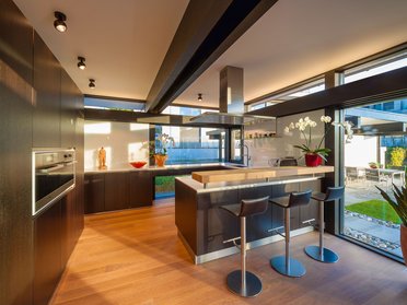 Helle, moderne Küche mit Barhockern und Pflanzen im Innenraum