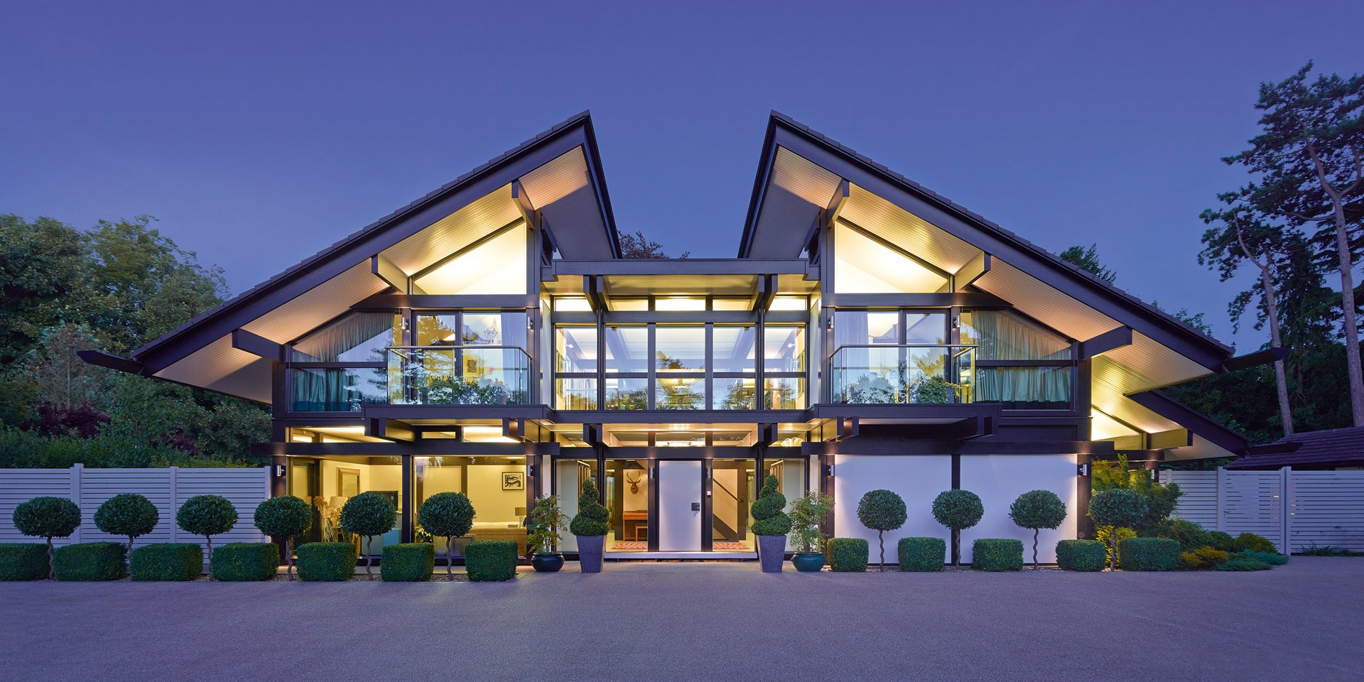Modernes Haus mit Glasfronten und stilvoller Landschaftsgestaltung bei Dämmerung