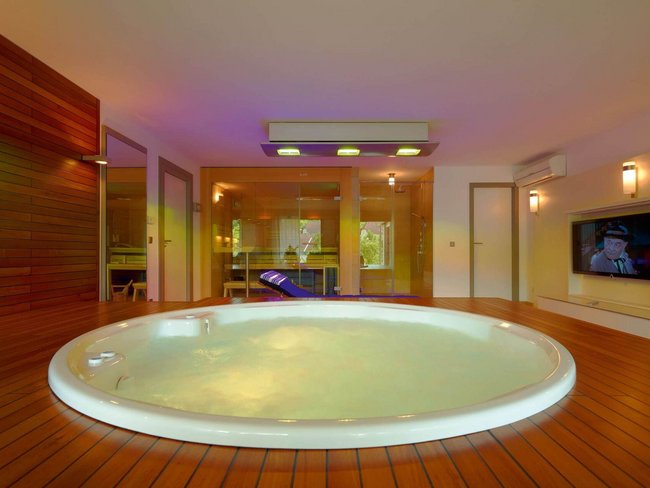 Wellnessbereich mit Whirlpool und stilvollem Holzinterieur in einem HUF HAUS