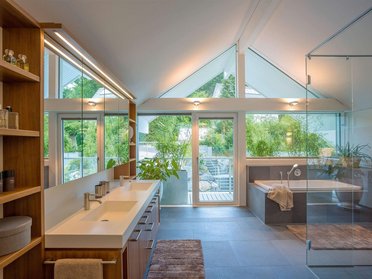 Helles Badezimmer mit großer Fensterfront und stilvollen Möbeln