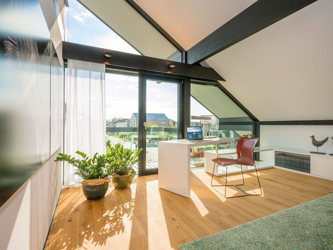 Helles Zimmer mit großen Fenstern, Pflanzen und minimalistischer Einrichtung