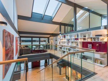 Innenansicht eines modernen Wohnraums mit großflächigen Fenstern und Regalen
