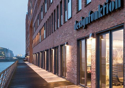 Architekturansicht eines Backsteingebäudes am Wasser mit Sicht auf Eingang