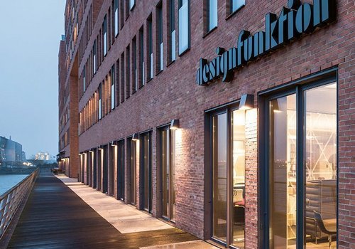 Architekturansicht eines Backsteingebäudes am Wasser mit Sicht auf Eingang