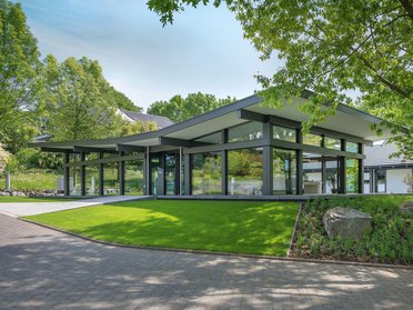 Moderne Architektur in einem grünen Umfeld Ein elegantes, modernes Gebäude umgeben von Bäumen und Rasen
